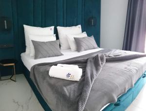 1 dormitorio con 1 cama grande con almohadas blancas y grises en EL Apartments - Solaris, en Poznan
