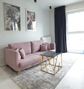 sala de estar con sofá rosa y mesa de cristal en EL Apartments - Solaris, en Poznan