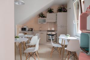 a small kitchen with white tables and white chairs at Intra Rooms in Olbia