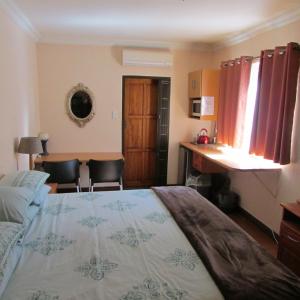 a bedroom with a bed and a table and chairs at Accommodation@Bourne in Centurion