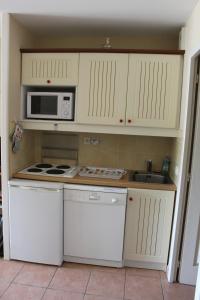 una cucina con armadi bianchi, forno a microonde e lavandino di Résidence du Lac-MONFLANQUIN Appartement RDC a Monflanquin