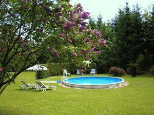 a swimming pool in a yard with chairs and a tree at Pension Pfefferdohle in Velden am Wörthersee