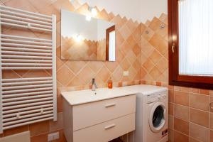 a bathroom with a sink and a washing machine at Appartamento Belvedere Citai in San Teodoro