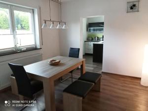 una cucina e una sala da pranzo con tavolo e sedie in legno di Ferienwohnung am Hopfengarten a Illschwang