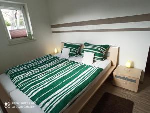 un letto con lenzuola e cuscini a righe verdi e bianche di Ferienwohnung am Hopfengarten a Illschwang