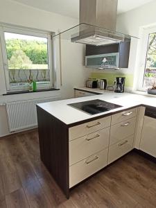 a kitchen with a stove top oven next to two windows at Ferienwohnung am Hopfengarten in Illschwang