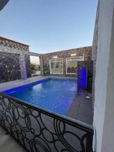 a large blue swimming pool on a balcony at Aljabal Al Akhdar Olive Tree Guest house in Al ‘Aqar