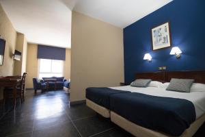 ロタにあるHotel Caribeの青い壁のベッドが備わるホテルルームです。