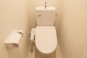 a white toilet in a bathroom with a roll of toilet paper at OSAKA SUNSHlNE TOWER23 in Osaka
