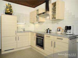 a kitchen with white cabinets and a stove top oven at Apartmenthaus Achenruh in Rauris