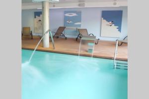 a swimming pool with chairs and a table in a room at Centrico apartamento en Noja con acceso a Spa in Noja
