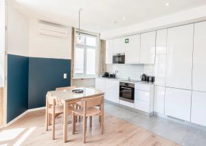 a kitchen with white cabinets and a wooden table and chairs at Mouzinho da Silveira Unique Apartments, by Oporto Collection in Porto