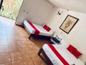 a room with two beds with red and white sheets at Hotel De Cervantes in San Sebastián del Oeste