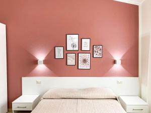 a bedroom with a pink wall with pictures on it at InCentro - San Teodoro in San Teodoro