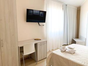 a bedroom with a bed and a desk with a television on the wall at InCentro - San Teodoro in San Teodoro
