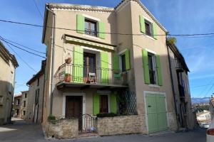 um edifício com persianas verdes numa rua em Maison de village Chez Mima Valensole em Valensole