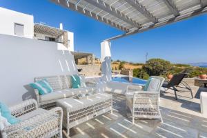 eine Terrasse mit weißen Möbeln und einem Pool in der Unterkunft Infinity Blue in Kampos Paros