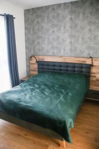 Bett mit grüner Decke in einem Schlafzimmer in der Unterkunft Morska fala, Jantar in Jantar