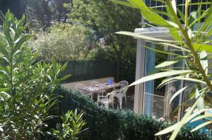 a patio with a table and chairs in a garden at Lara 6 - Grand T2 Terrasse Loggia - WC indép - Parking - Quartier calme entre centre-port et île des Loisirs plage Richelieu in Cap d'Agde +26 photos