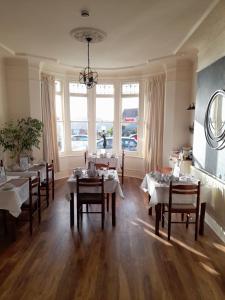 a dining room with tables and chairs and windows at Tregella Guest House in Newquay