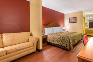 a hotel room with a bed and a couch at Econo Lodge Inn & Suites Maingate Central in Kissimmee +21 photos