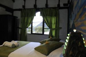 1 dormitorio con 1 cama con cortinas verdes y ventana en Hostal Inti Luna, en Baños