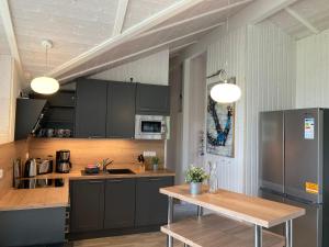uma cozinha com armários pretos e uma mesa de madeira em Strandhus - Haus 37 em Grömitz