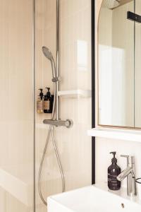 a shower in a bathroom with a sink and a mirror at Hôtel Maison Traversière in Paris