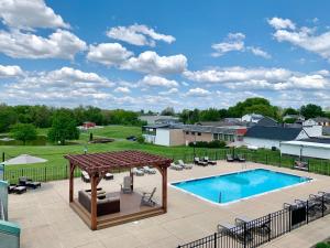 an outdoor swimming pool with a pavilion and a patio with chairs at The Inn at Hershey Farm in Ronks
