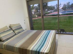 a bedroom with a bed and a cat looking out the window at Appartement perla saidia in Saïdia