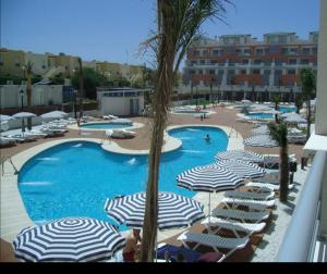 a large swimming pool with umbrellas and chairs in a resort at Marina Rey Aparthotel Playa de Puerto Rey in Vera