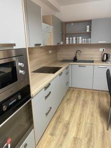 a kitchen with white cabinets and a microwave at Apartmán Solax, Učňovská 8, Košice Šaca in Košice