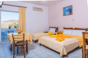 a hotel room with two beds and a table and chairs at Arsinoi Studios and Apartments in Kalamaki