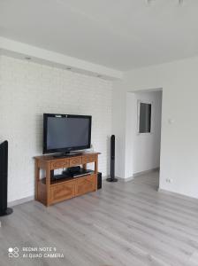 a flat screen tv sitting on a wooden stand in a room at Apartament Blisko Zamku in Malbork