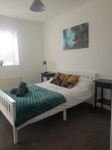 a bed with a green blanket and pillows on it at Cherry Tree, Centrally Located Warrington Town Centre in Warrington