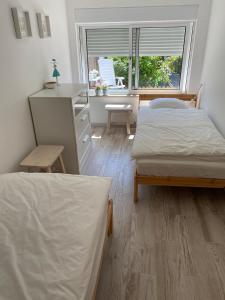 a bedroom with two beds and a desk and a window at Guest House AltoNível in Viana do Castelo