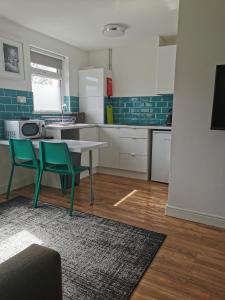 a kitchen with a table and two green chairs at Stylish studio bungalow, close to Cardiff Centre in Cardiff