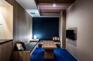 a room with a bench and a table and a tv at Homm Stay Nagi Shijo Kyoto By Banyan Group in Kyoto