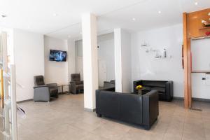 una sala de espera con sofás, sillas y TV en Hotel Hansa Stuttgart City en Stuttgart
