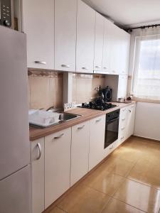 a kitchen with white cabinets and a sink at Forest Apartment Timișoara in Timişoara