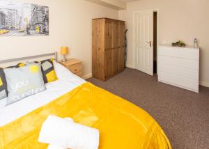ein Schlafzimmer mit einem gelben Bett und einer Kommode in der Unterkunft Ample Comforts, Centrally Located, Town Centre in Warrington