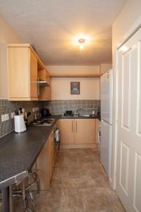 a kitchen with wooden cabinets and a white refrigerator at Ample Comforts, Centrally Located, Town Centre in Warrington