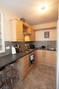 a kitchen with wooden cabinets and a counter top at Ample Comforts, Centrally Located, Town Centre in Warrington +9 photos
