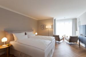 a hotel room with a large white bed and two chairs at Vju Hotel Rügen in Göhren