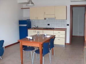 リニャーノ・サッビアドーロにあるApartment in Lignano 21644のキッチン(木製テーブル、青い椅子付)