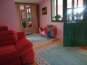 a living room with a red chair and a door at Hello Nature House - Cheile Nerei, Carasului, Garlistei in Giurgiova