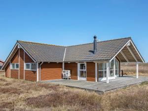 una casa de madera con terraza en un campo en Holiday home Lemvig XXVIII, en Lemvig