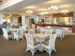 una sala da pranzo con tavoli e sedie bianchi di Carlisle Inn a Sugarcreek