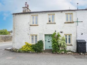 a white brick house with a green door at Tyee Cottage in Carnforth