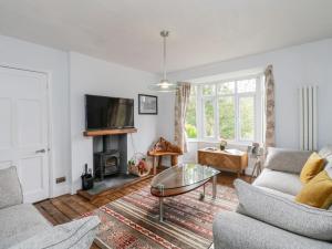 ein Wohnzimmer mit einem Sofa und einem Tisch in der Unterkunft Hunter's Cottage in Windermere